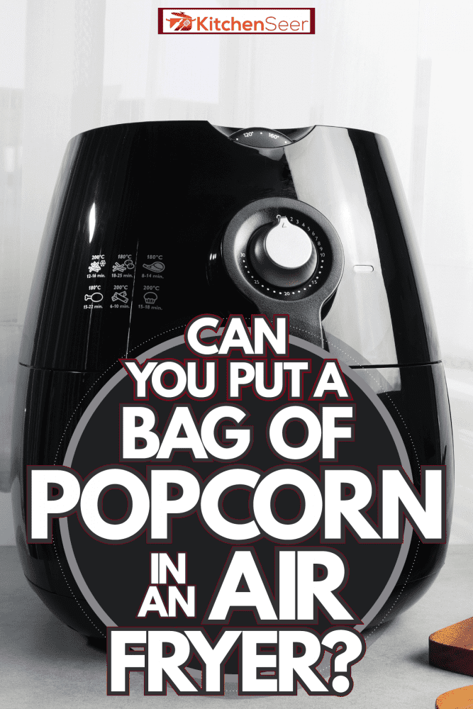 A black air fryer with a chopping board on the side, Can You Put A Bag Of Popcorn In An Air Fryer? 