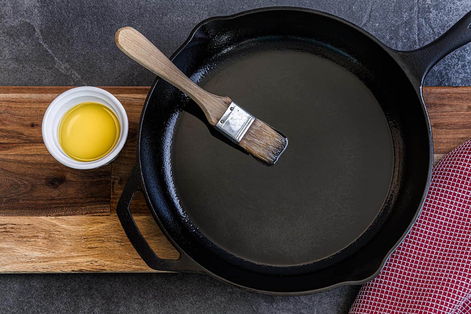 Cast iron skillet being brushed with olive oil to prevent sticking