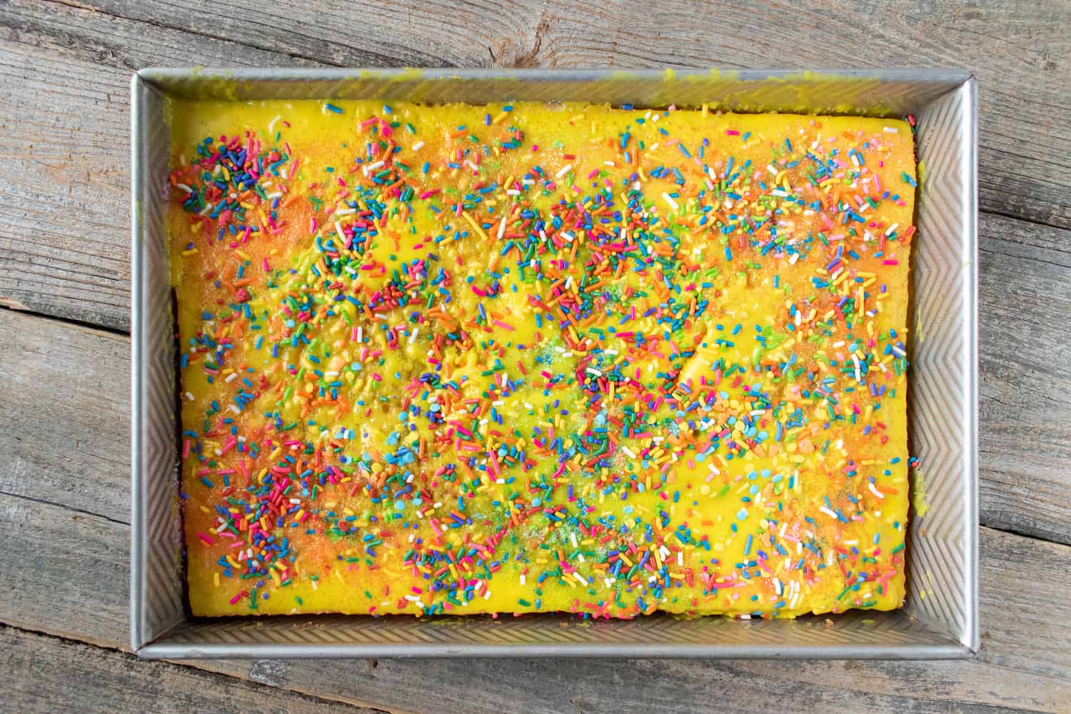 Colorful sprinkle yellow sheet cake in rectangle pan flat lay