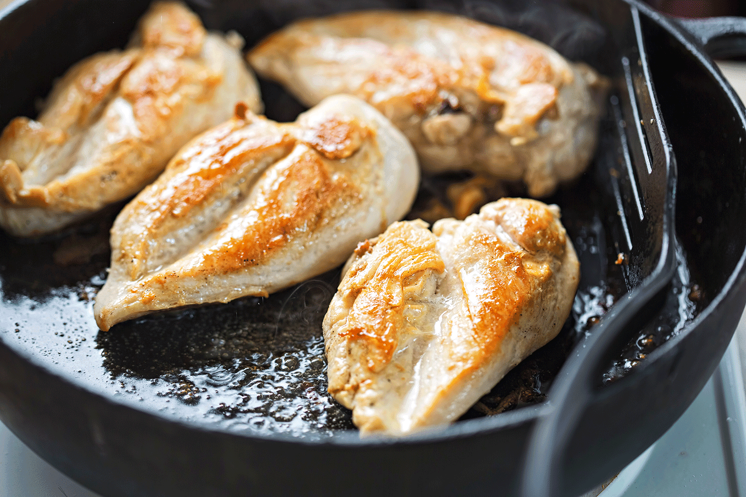 Fried chicken breasts on vegetable oil, iron cast pan
