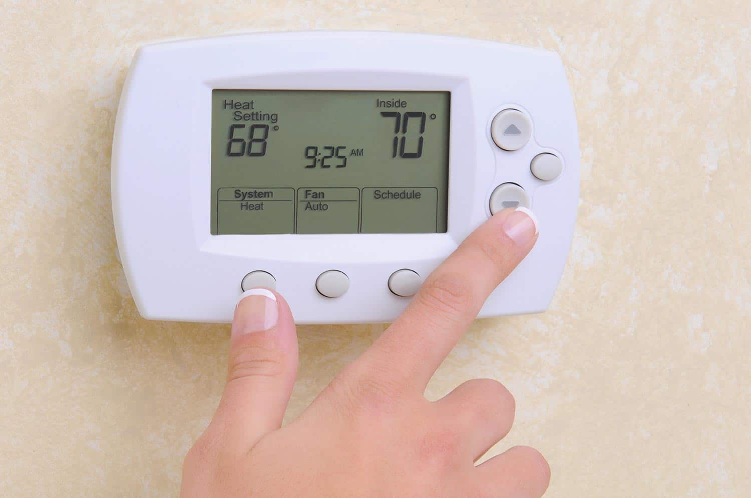 Hand setting the room temperature on a modern programable thermostat