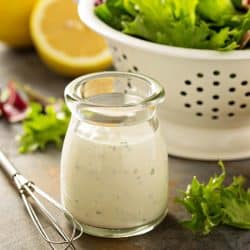 A homemade lemon ranch dressing in a small jar with fresh greens, How To Thin Out Ranch Dressing [Store Bought Or Homemade]