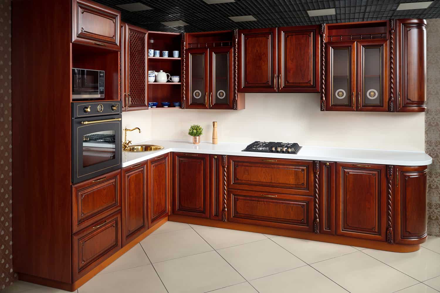 Interior of modern kitchen in classic style with golden elements cherry alder wood cabinetry with built-in appliances electric or induction hob, electric oven stone sink and extractor fan.