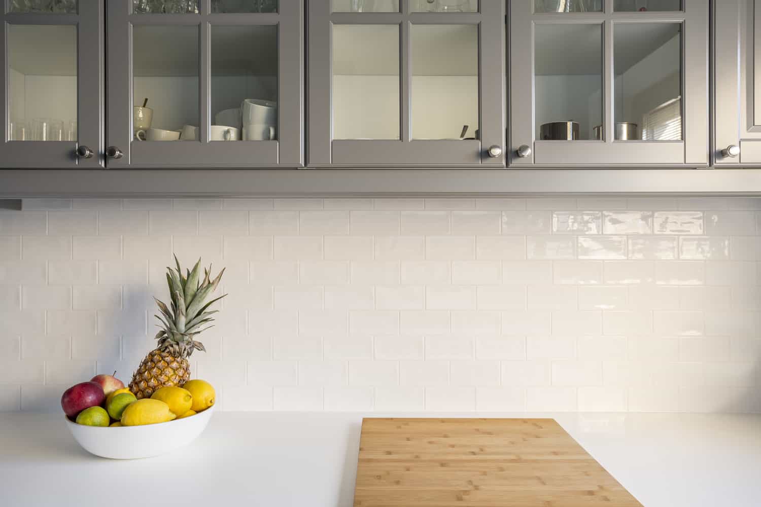 Kitchen with white worktop, grey furniture and brick tiles