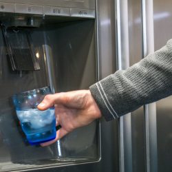 Man taking a glass of water from the dispenser, Can A Refrigerator Filter Well Water?