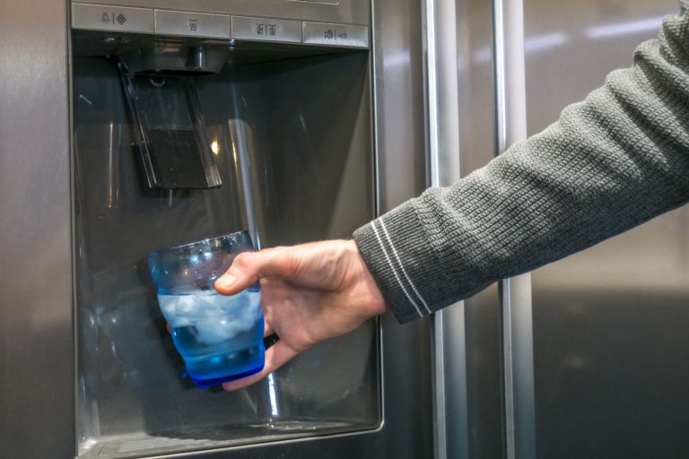 Man taking a glass of water from the dispenser, Can A Refrigerator Filter Well Water?