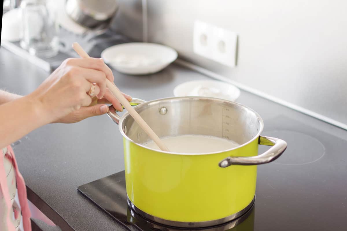 Mixing boiling milk on a wooden spoon for proper process for a boiled milk
