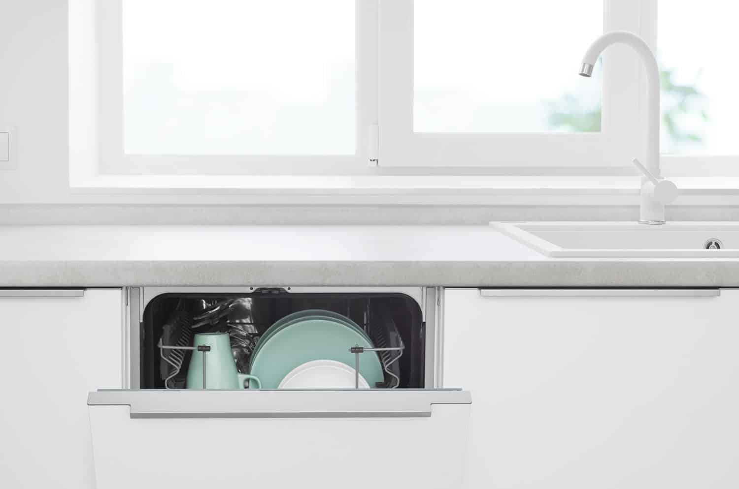Opened door of build-in dishwasher on modern kitchen counter