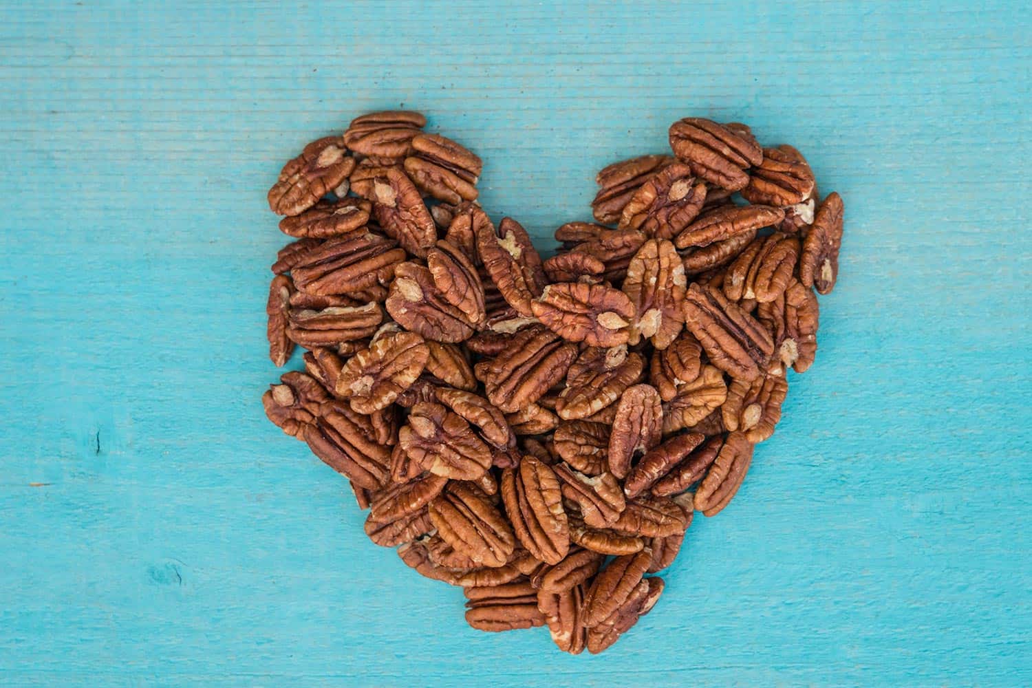 Pecan nuts make heart on turquoise table