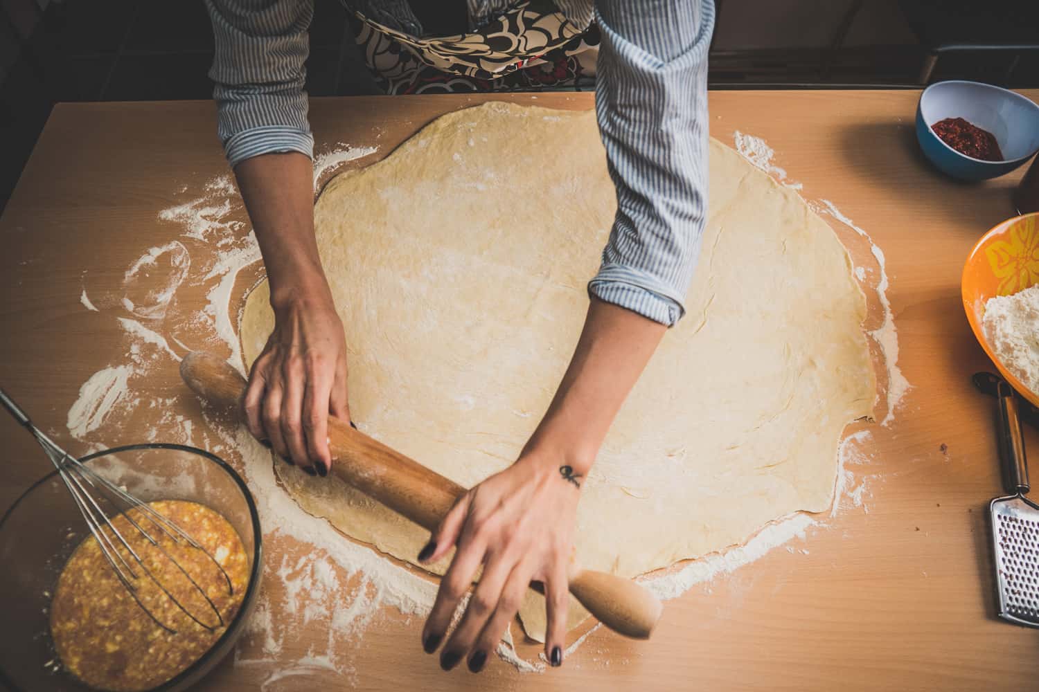 Photo of baker kneading dough with rolling pin for handmade rolls
