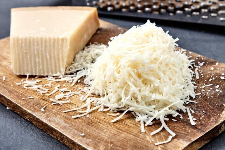 A piece and grated parmigiano reggiano or parmesan cheese on wood board, Can You Grate Cheese Ahead Of Time?