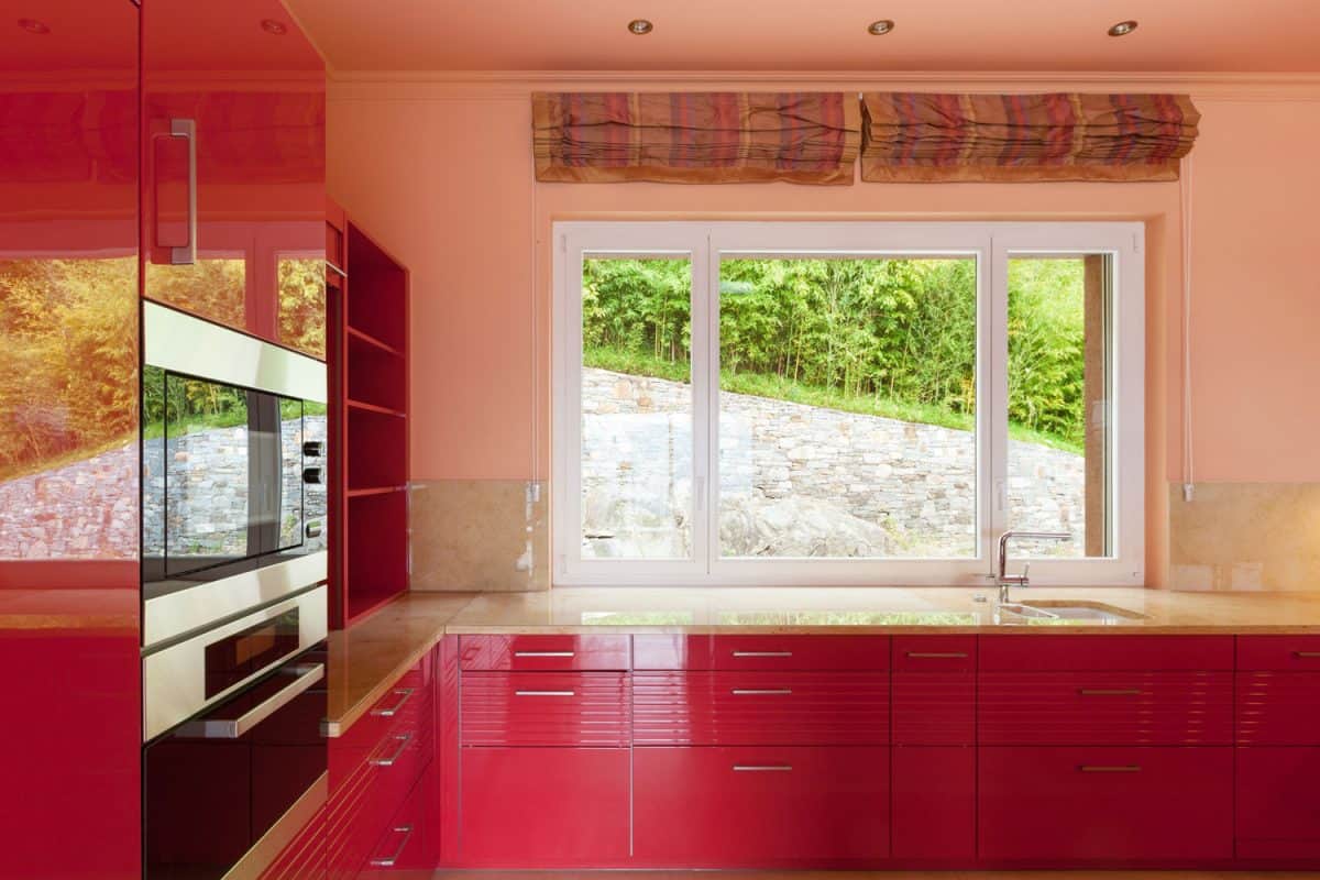 Red aluminum panels on the kitchen cabinets with matching brown marble countertop