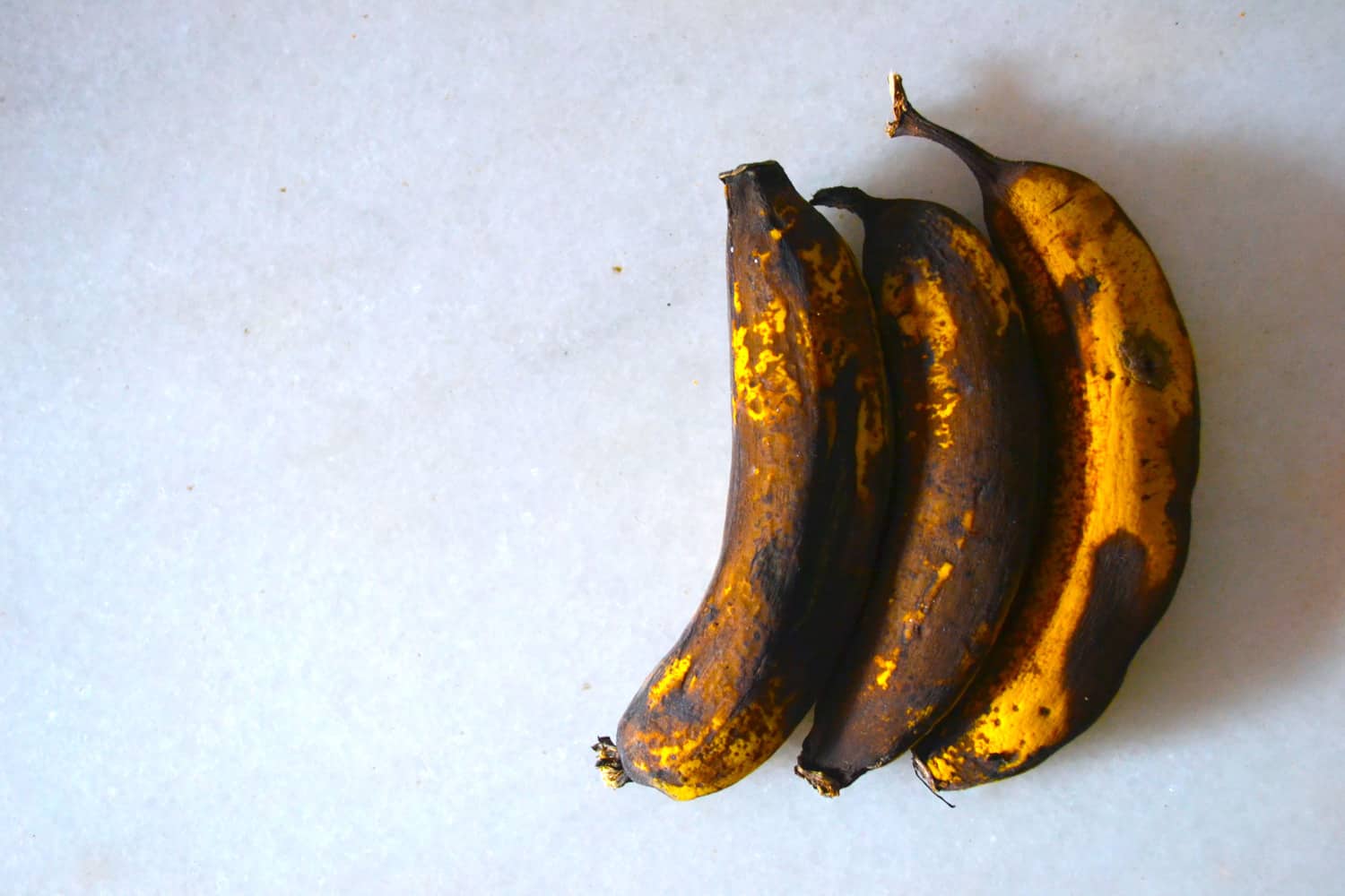 Rotten brown bananas on white marble