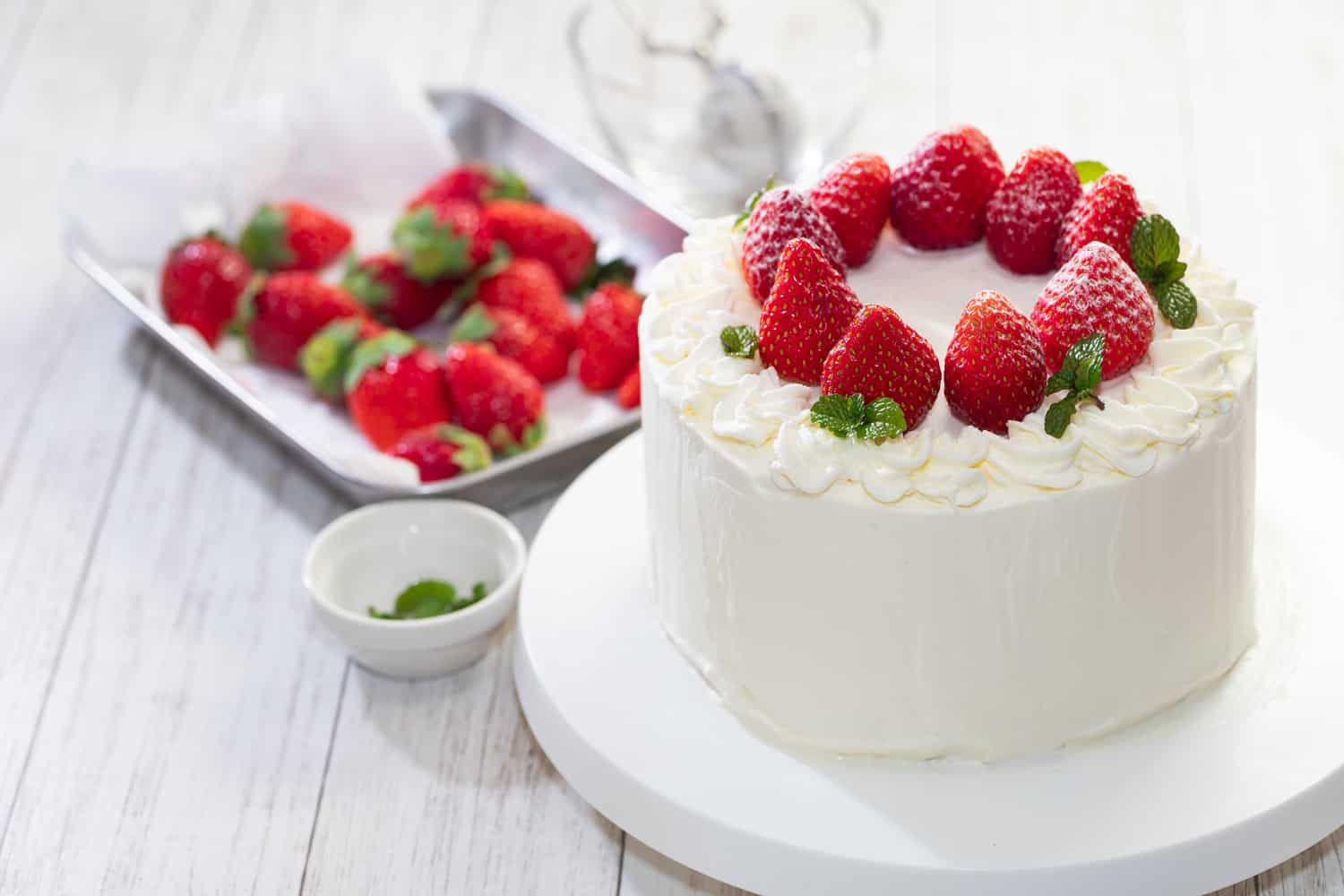 Strawberry and cream sponge cake on white wooden table
