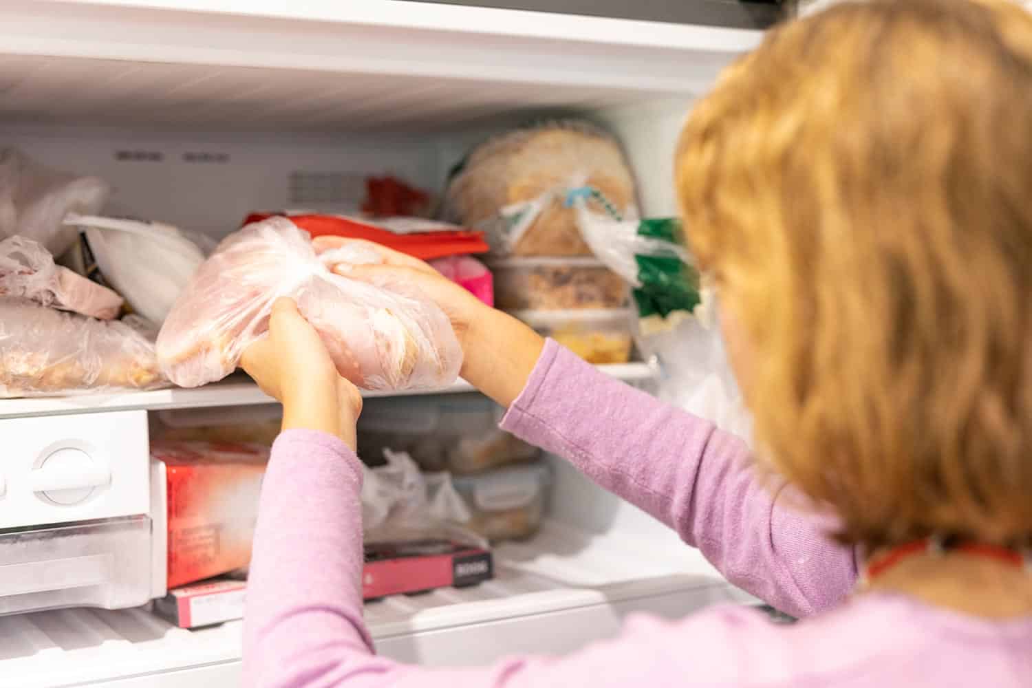 Teenager putting meat in a freezer