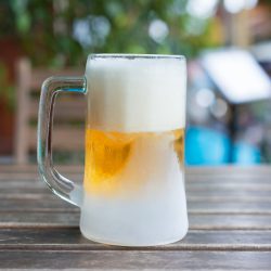 The Frozen mug of cold light beer at the pub wooden table, close up, Acrylic Vs. Polycarbonate Drinking Glasses: Which To Choose?