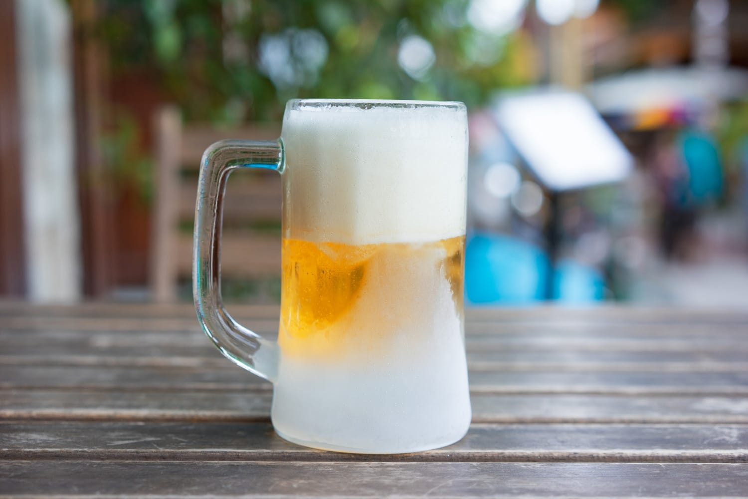The Frozen mug of cold light beer at the pub wooden table, close up
