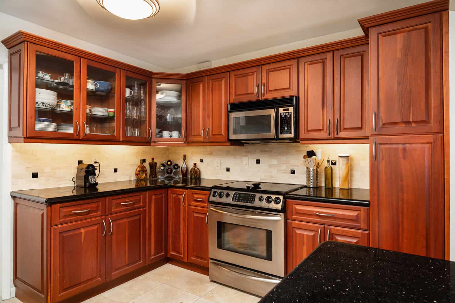 Traditional cheery wood cabinet home kitchen with a black granite countertop.