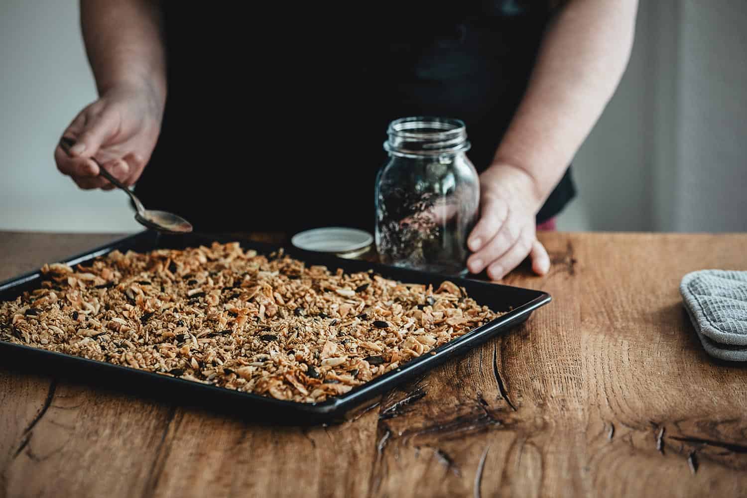 Woman filling a glass jar with homemade granola