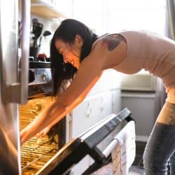 A woman preparing food on the kitchen, Does Using The Oven Heat Up The House?
