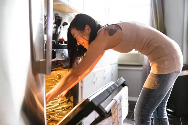A woman preparing food on the kitchen, Does Using The Oven Heat Up The House?