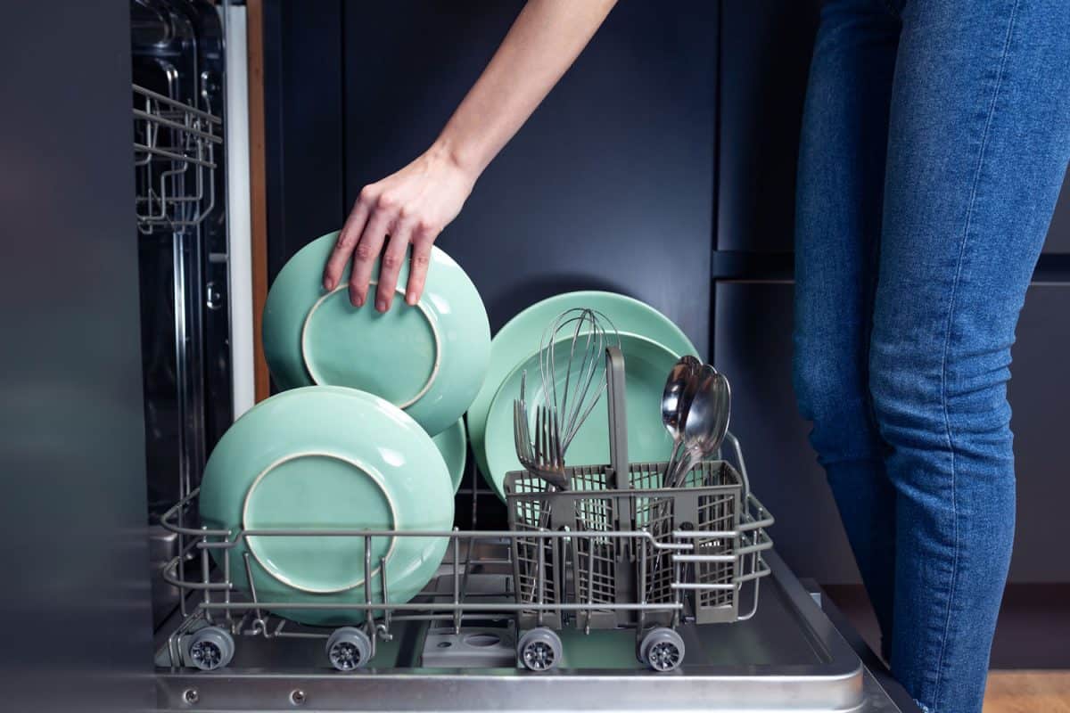 Woman putting plates inside the dishwasher