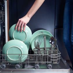 Woman putting plates inside the dishwasher, Can You Run A Dishwasher Without Hot Water?