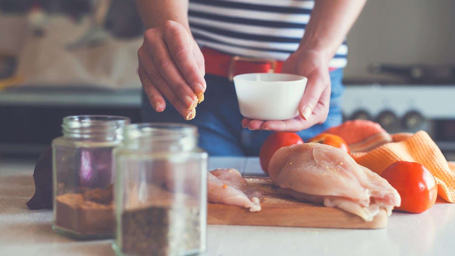Young woman preparing chicken meat