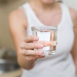 a healthy young woman holds a glass of water. clean drinking water in a clear glass in your hands close-up, How Much Does A Drinking Glass Weigh?