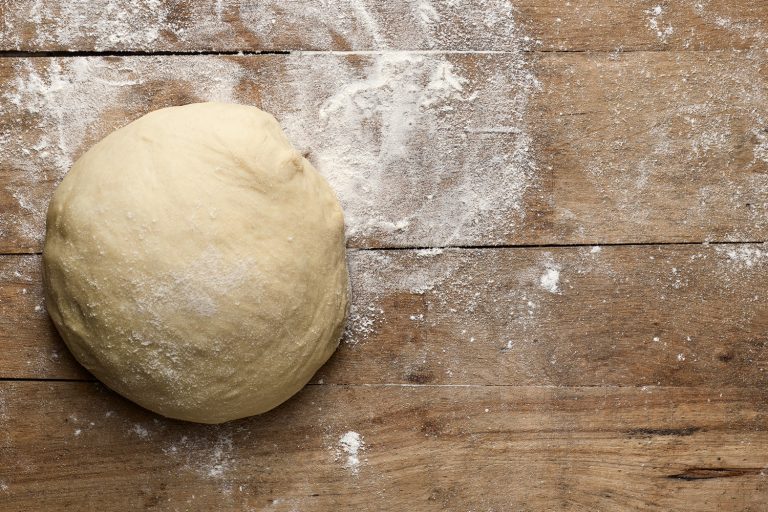 fresh raw pizza dough on rustic wooden table - How Long Does It Take To Make Pizza Dough