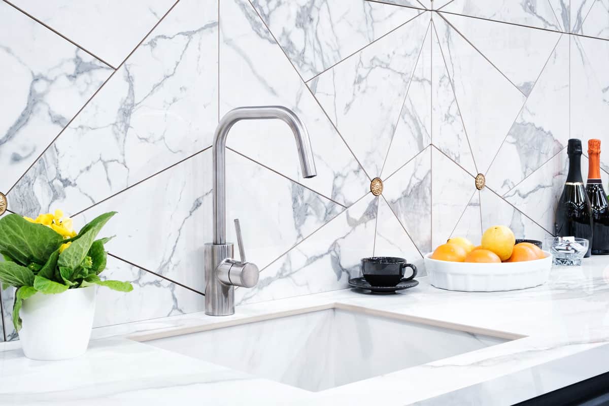interior of the modern kitchen is illuminated with a gray stone countertop with a luxury washbasin