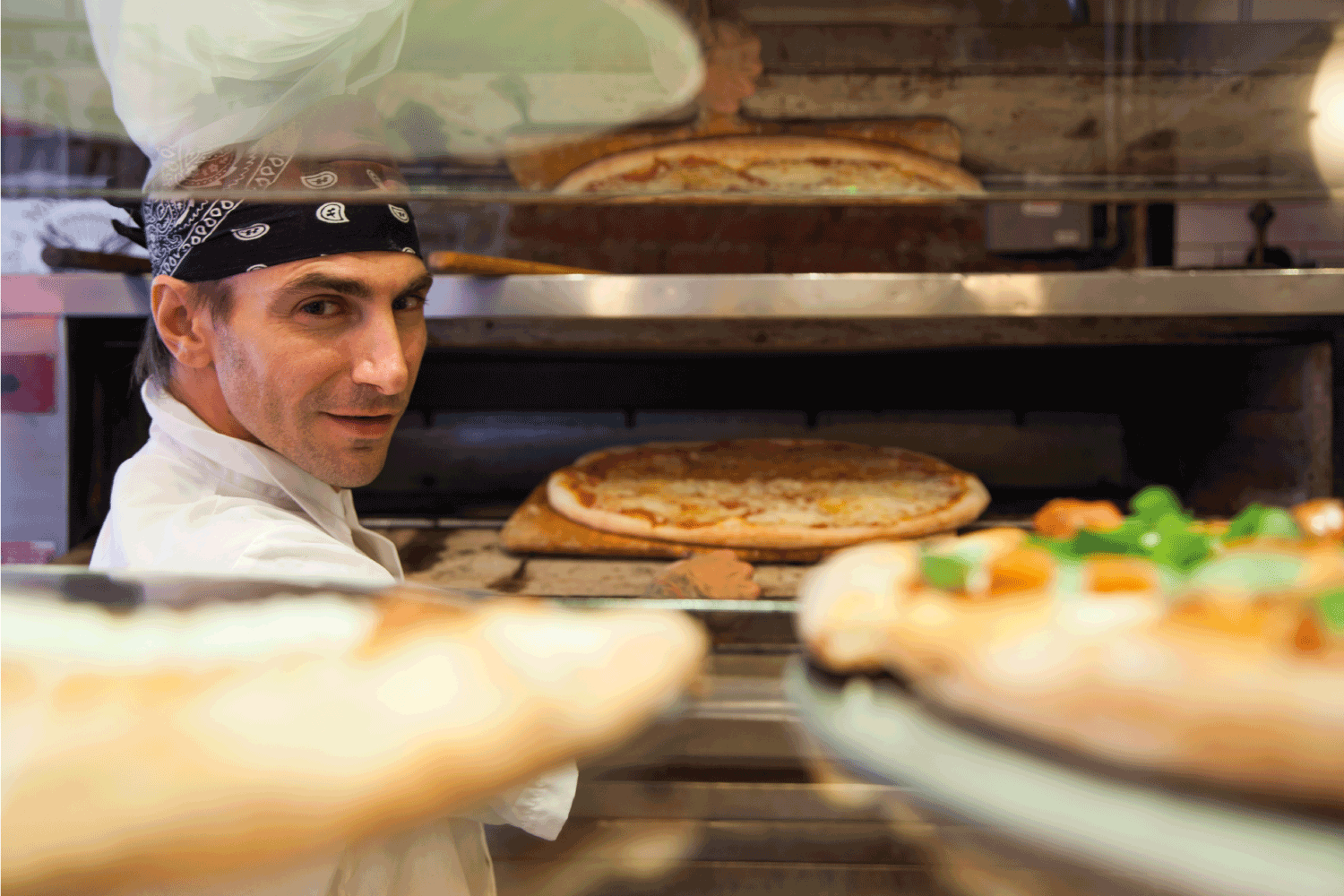 pizza chef inside his kitchen infront of a large oven