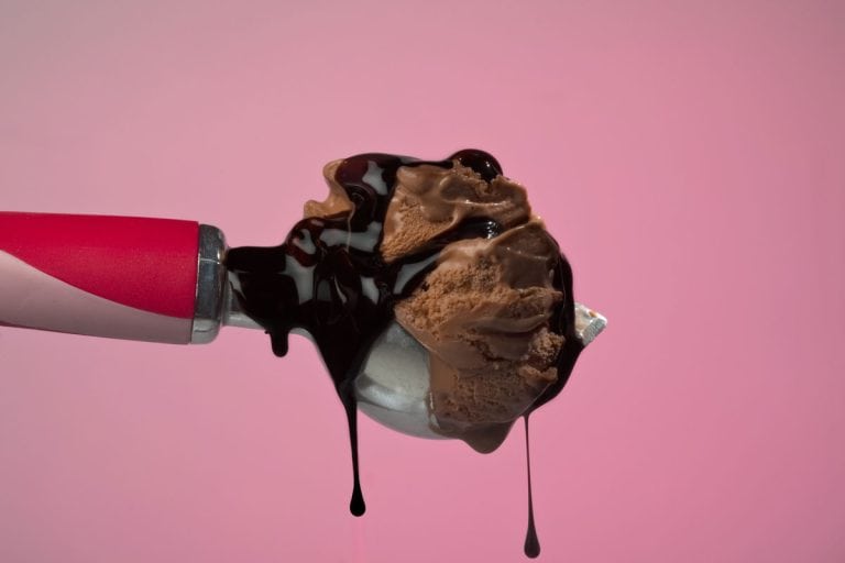 A big scoop of real chocolate ice cream and dripping fudge sauce on a pink background, How Many Ounces In An Ice Cream Scoop?
