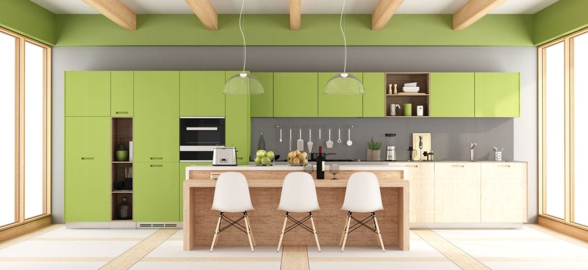 A breakfast bar with white Nordic stool chairs matched with green cabinets on a gray wall