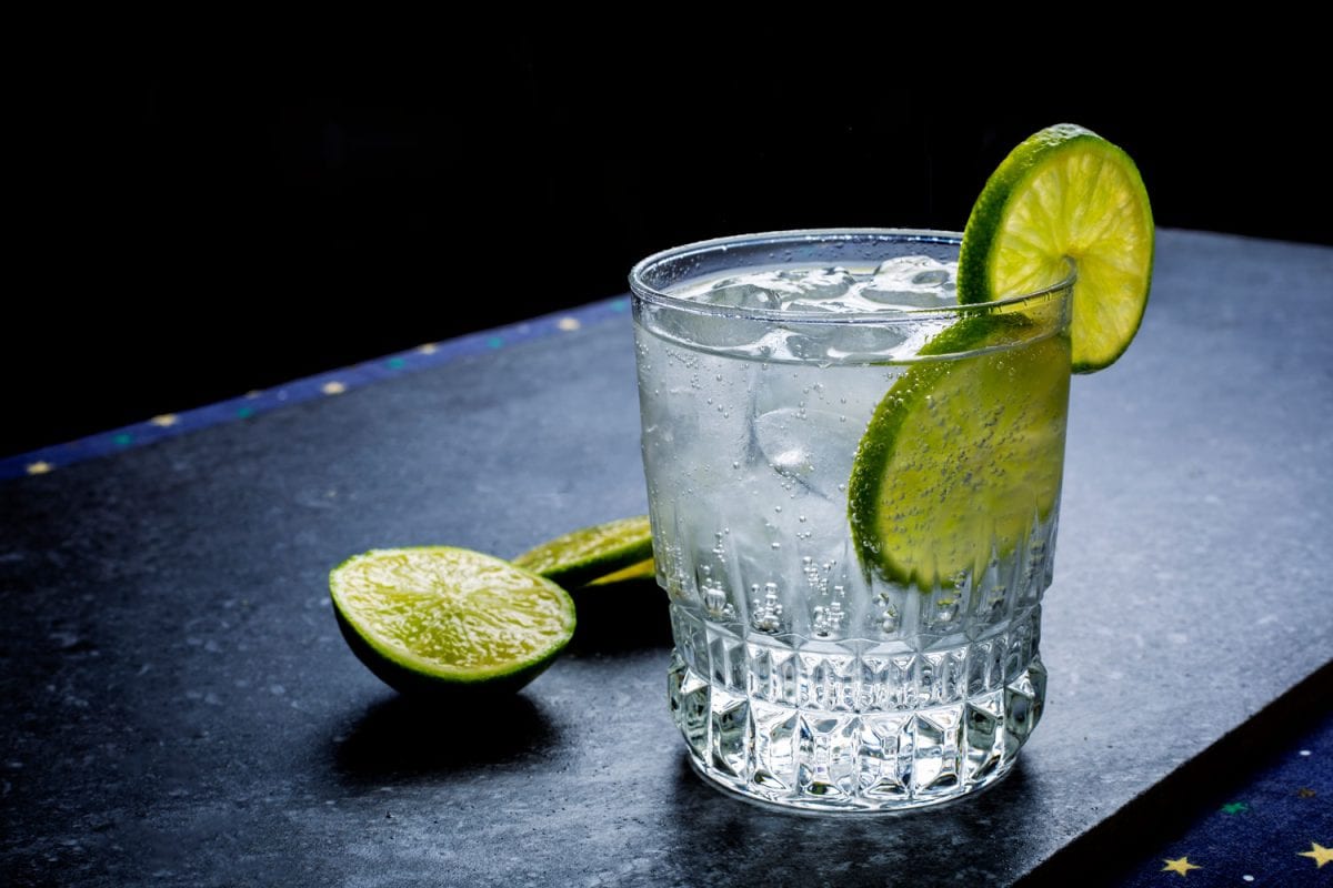 A glass with ice, gin and lime