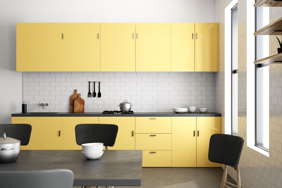 A gray and yellow painted kitchen cabinets and cupboards with brick backsplash