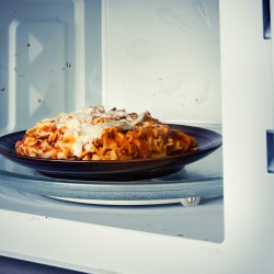 A plate of leftover lasagna is reheated in a microwave - How Long To Bake Lasagna