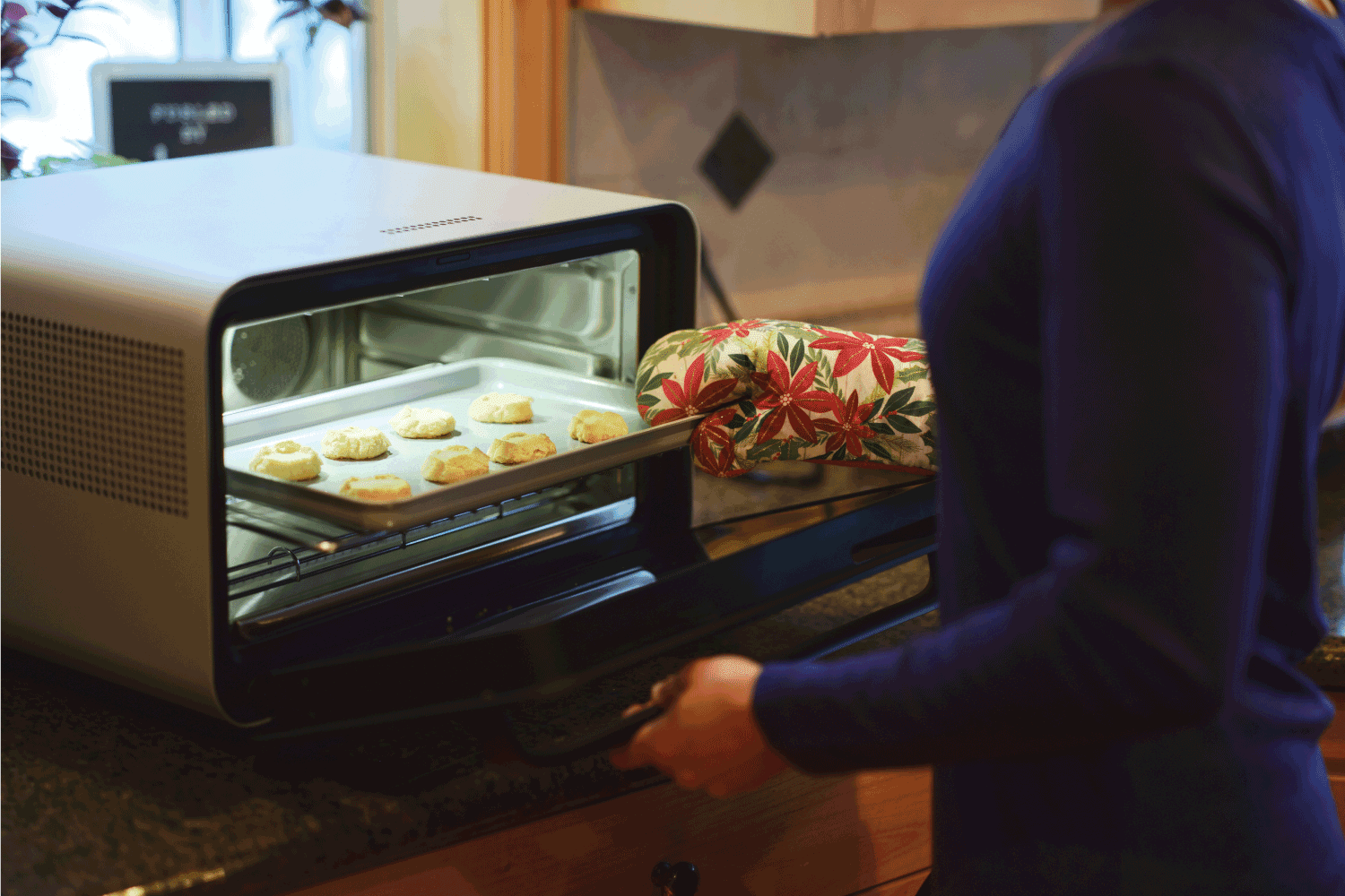 A woman using a countertop oven in her home kitchen.