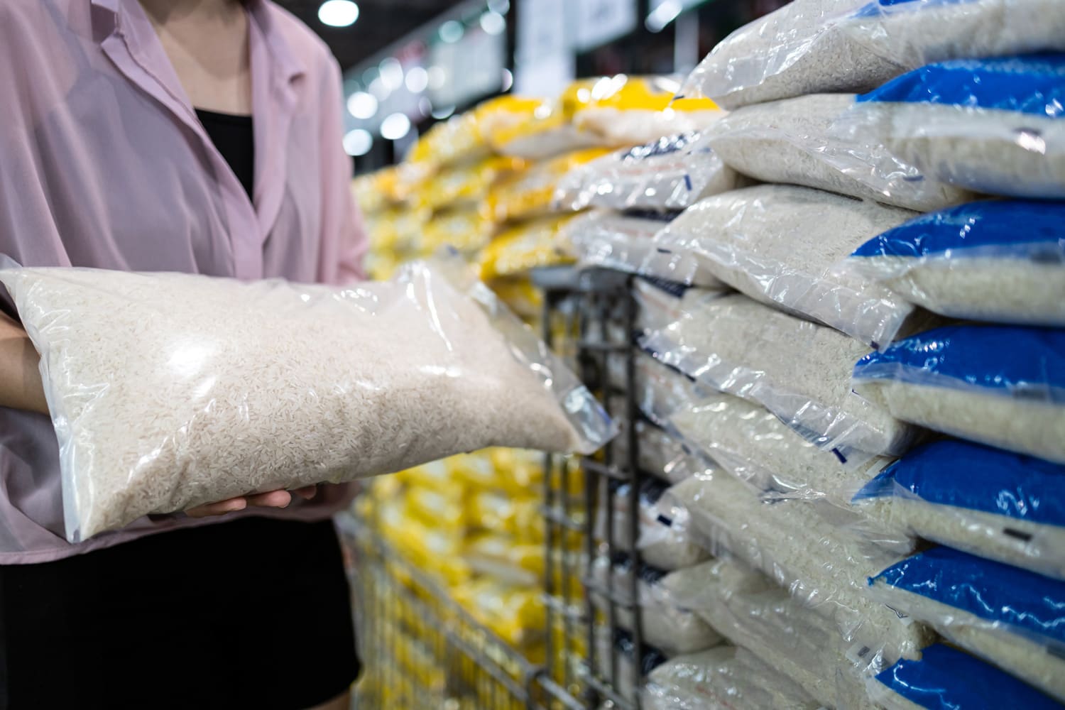 Close up of hands,Asian female consumer holding white rice,shopping dry food,girl buying jasmine rice in transparent plastic bag,choose raw rice products packed for sell at supermarket,food nutrition