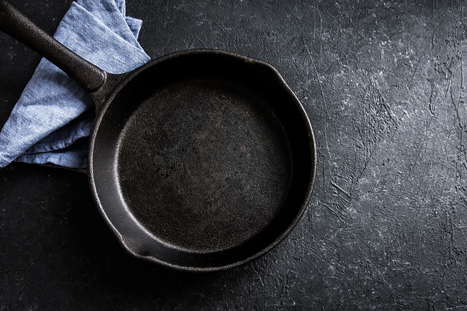 Cast iron pan on rustic black stone background close up - empty black frying pan frying skillet with copy space