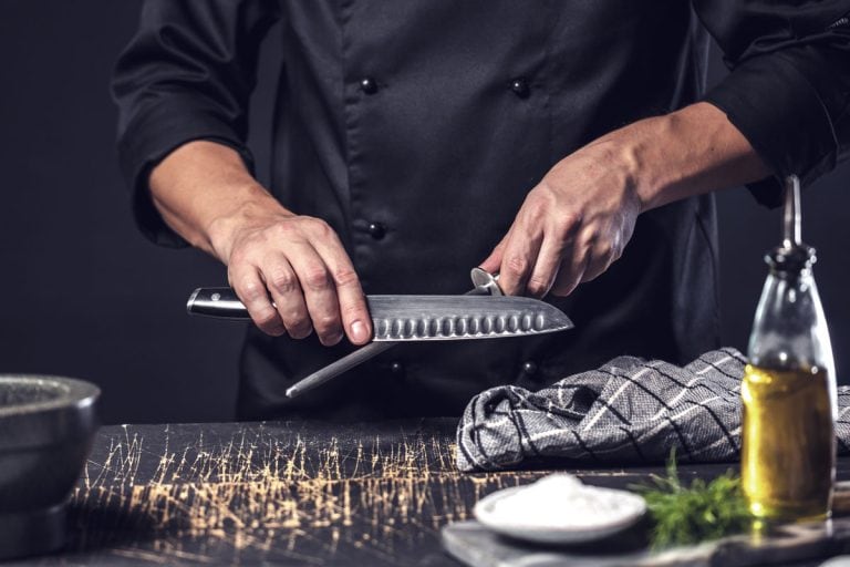 Chef cook holds a knife over dark grey background
