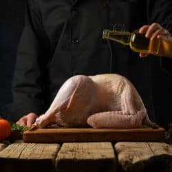 Chef pouring an olive oil in a turkey, What's The Best Oil To Deep Fry Turkey?