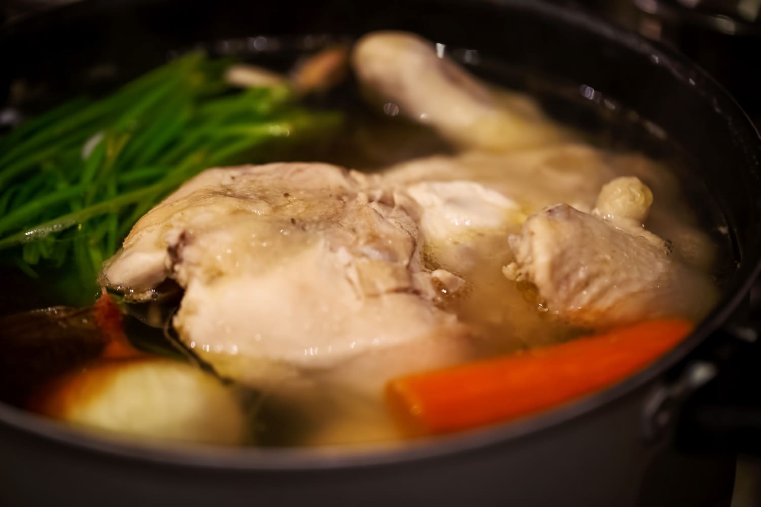Cooking chicken broth with vegetables in large pot