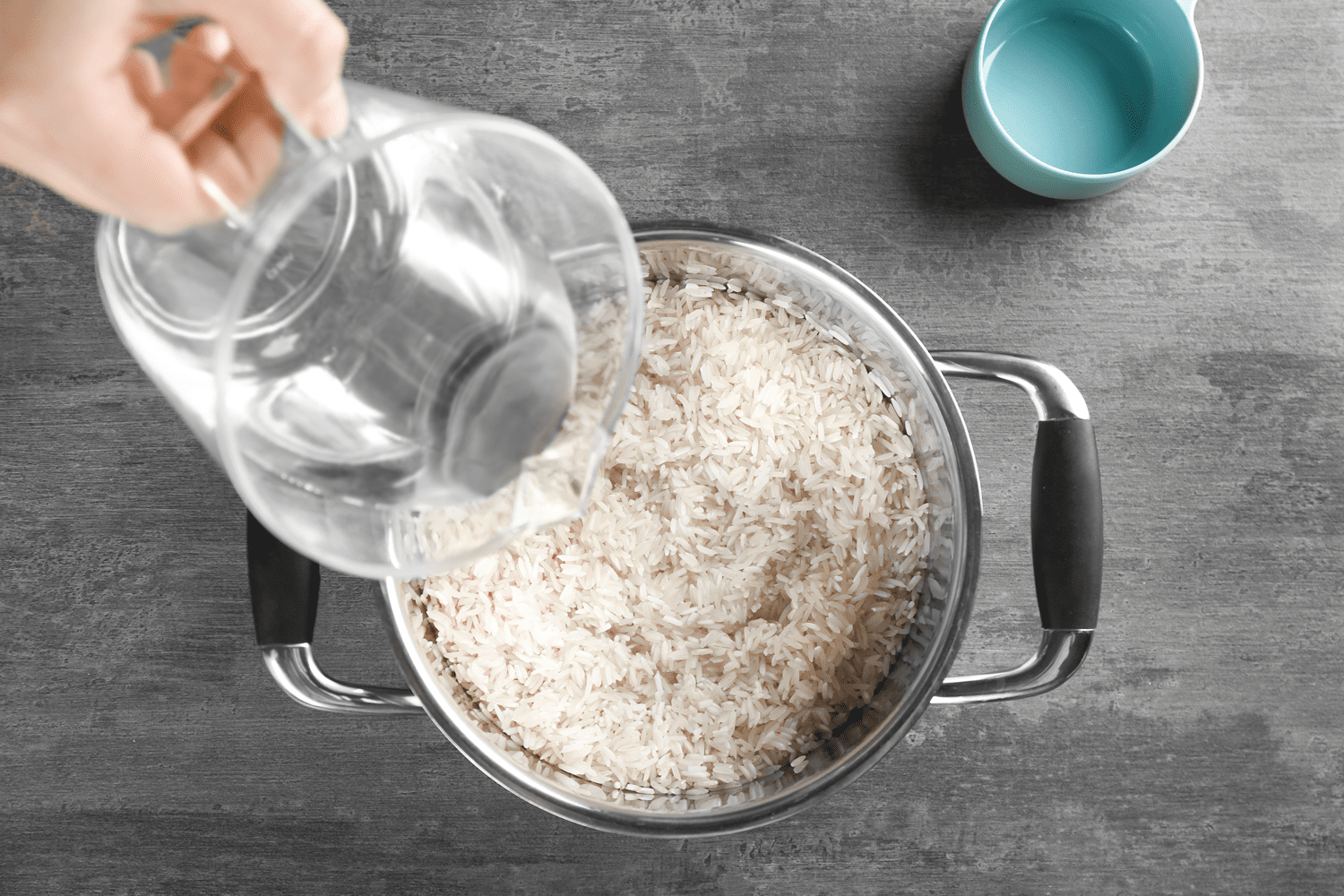 Cooking concept. Pouring water in saucepan with rice