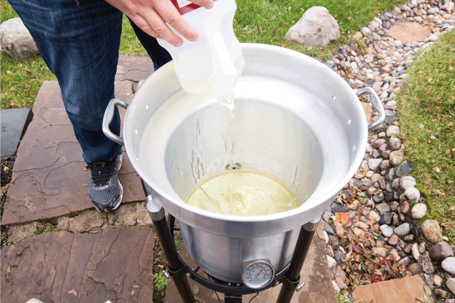 Cooking oil being poured into an outdoor deep fryer. This is being done in preparation of cooking a turkey for Thanksgiving