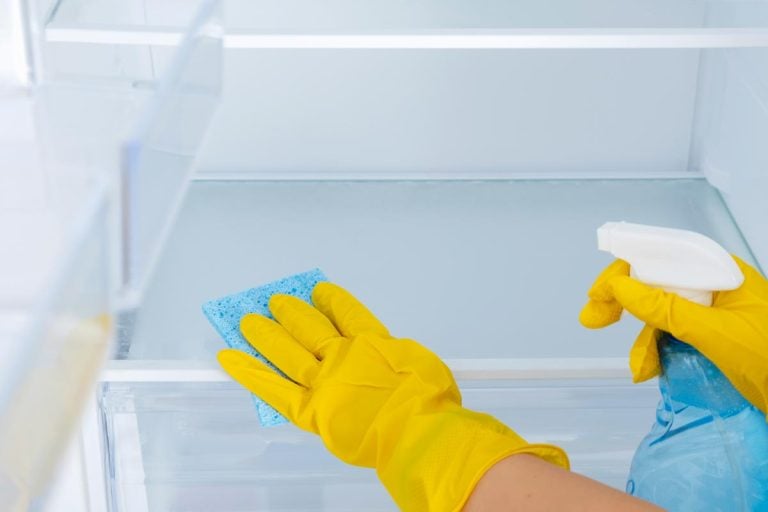 A female with yellow rubber protective glove and a blue sponge cleaning freezer, How To Clean Exploded Pop In Freezer