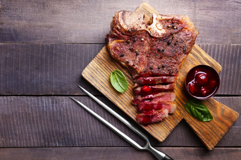 Grilled steak with sauce on cutting board, top view, Should You Rinse Salt Off Steak Before Cooking?