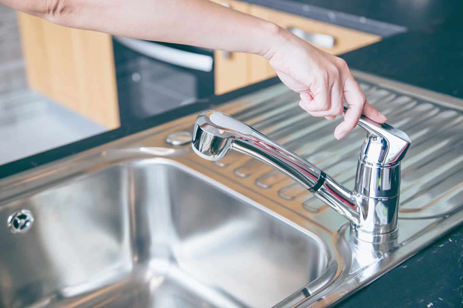 Hands are close faucet chrome water. kitchen faucet polished chrome and sink polished chrome. object about home Improvement.