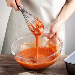 Man mixing orange food coloring in a glass mixing bowl, How To Thin Gel Food Coloring