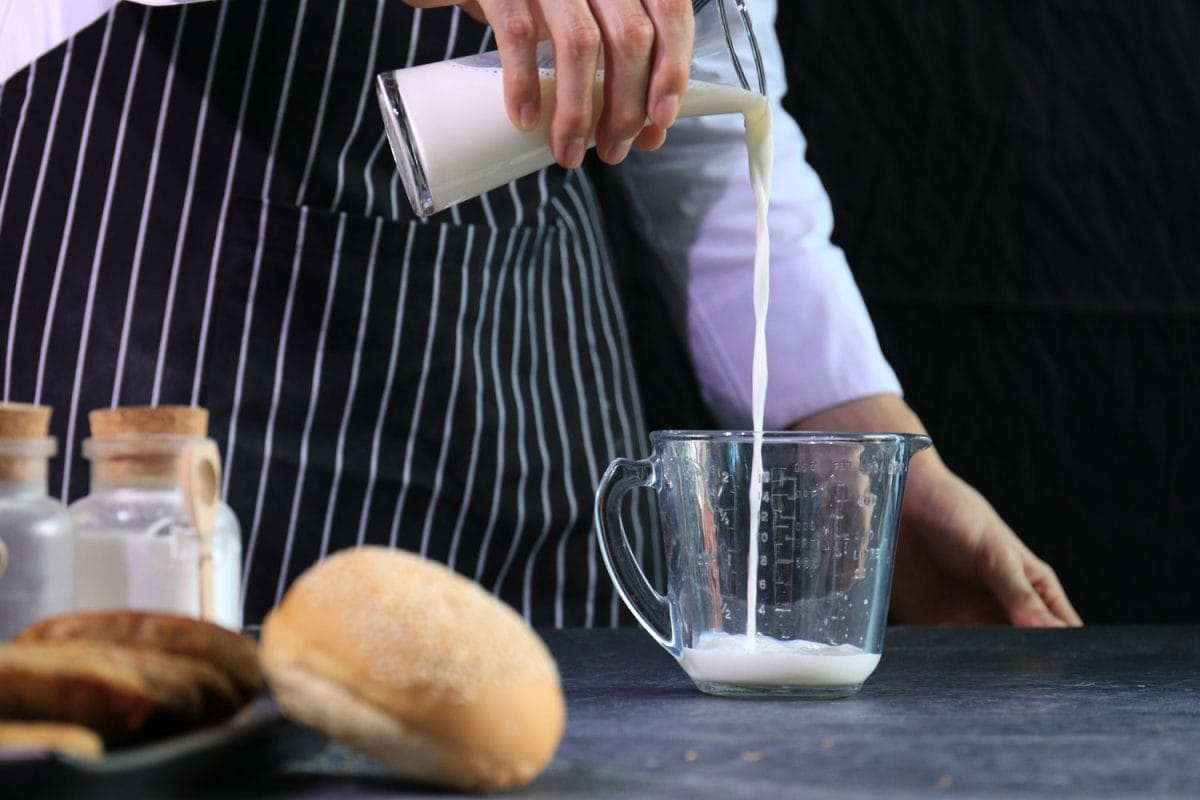 Pastry chef putting milk into a measuring cup